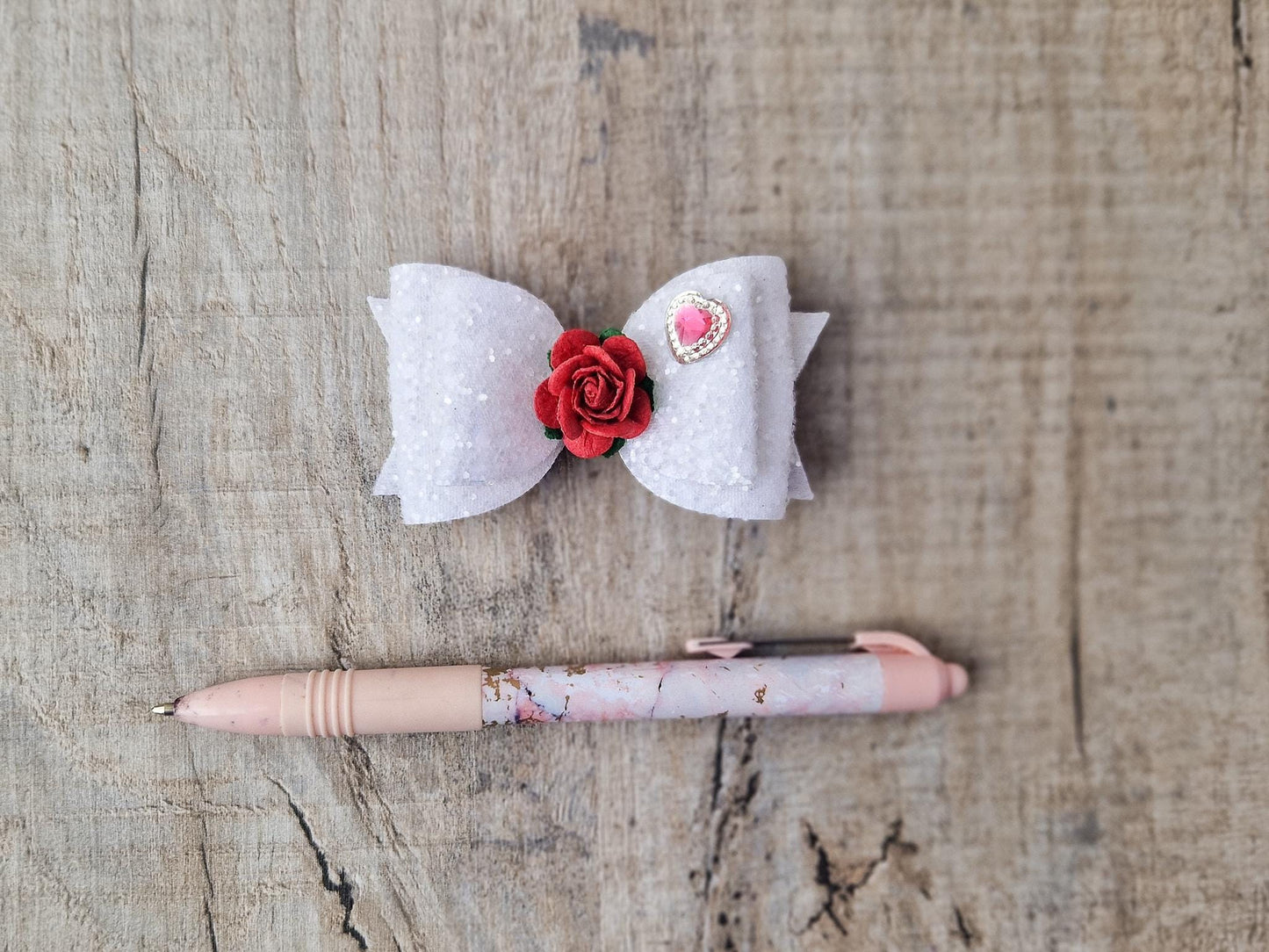 Beautiful Girls hair bow made with white Glitter and finished with a red rose and pink heart embellishment.