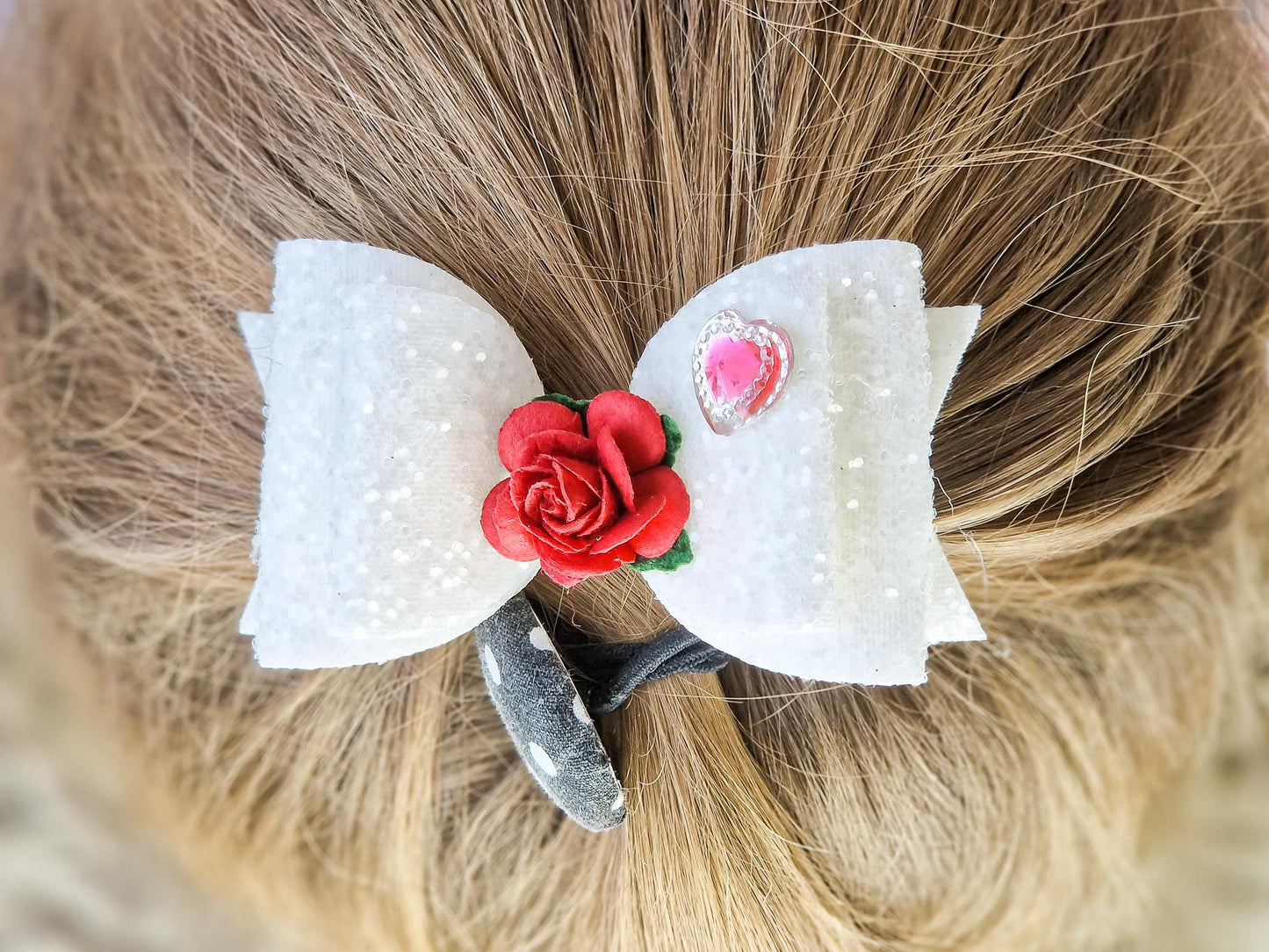 Beautiful Girls hair bow made with white Glitter and finished with a red rose and pink heart embellishment.