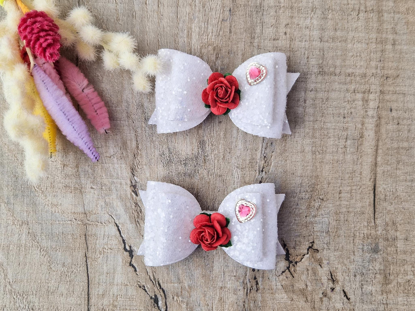 Beautiful Girls hair bow made with white Glitter and finished with a red rose and pink heart embellishment.