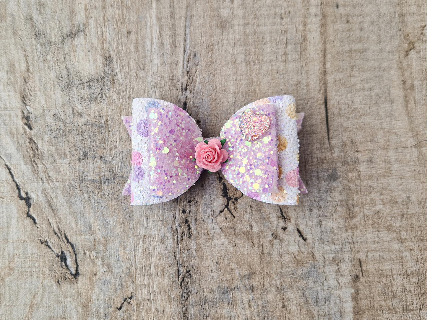 Glitter Hair bow, in pink Pastel glitter colours with a heart and flower Embellishment.