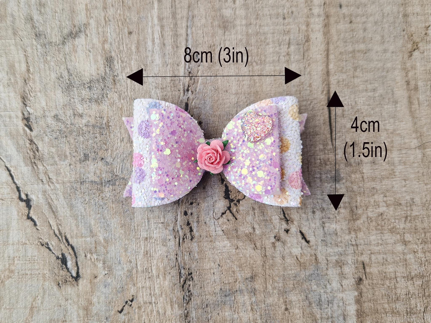 Glitter Hair bow, in pink Pastel glitter colours with a heart and flower Embellishment.