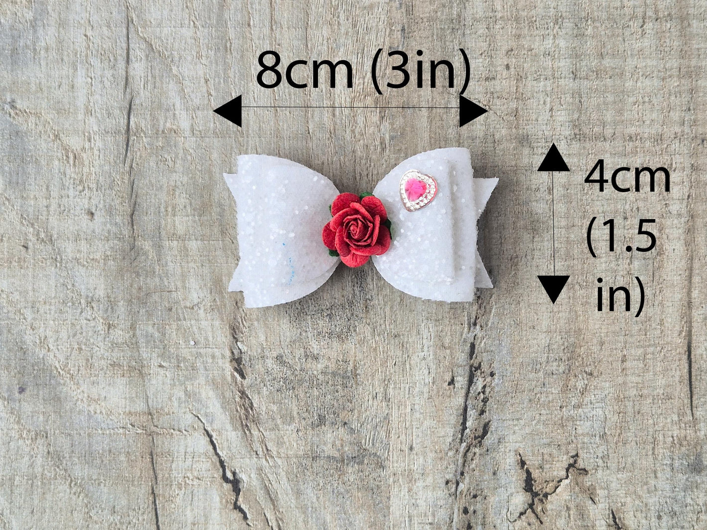 Beautiful Girls hair bow made with white Glitter and finished with a red rose and pink heart embellishment.