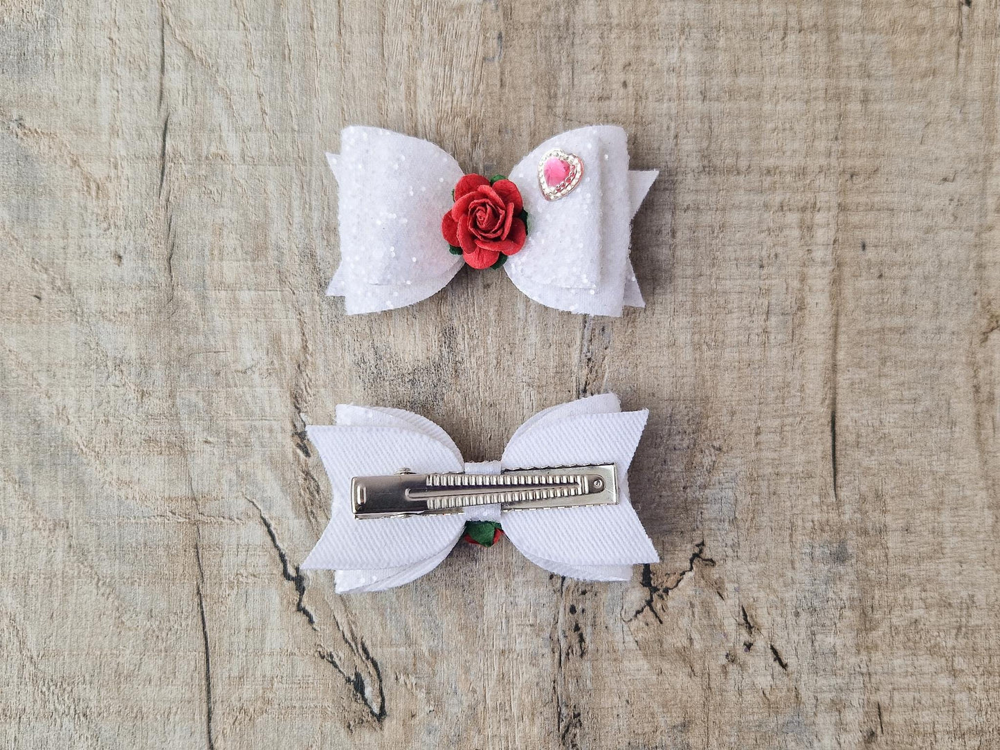Beautiful Girls hair bow made with white Glitter and finished with a red rose and pink heart embellishment.