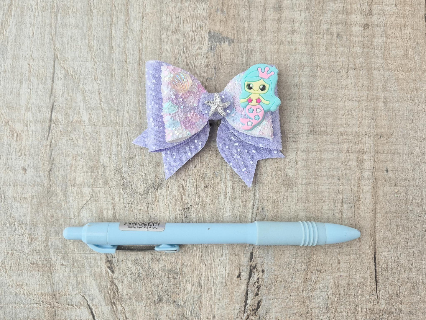 Blue Mermaid Glitter Hair bow embellished with a Mermaid, star fish and sea shell.