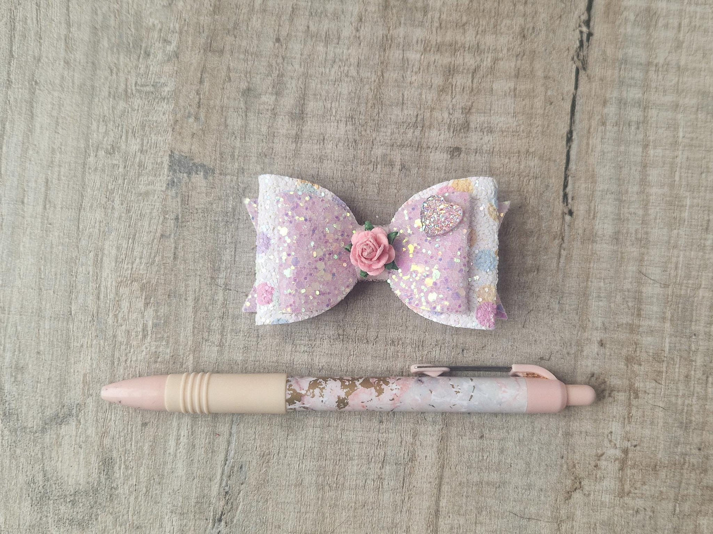 Glitter Hair bow, in pink Pastel glitter colours with a heart and flower Embellishment.