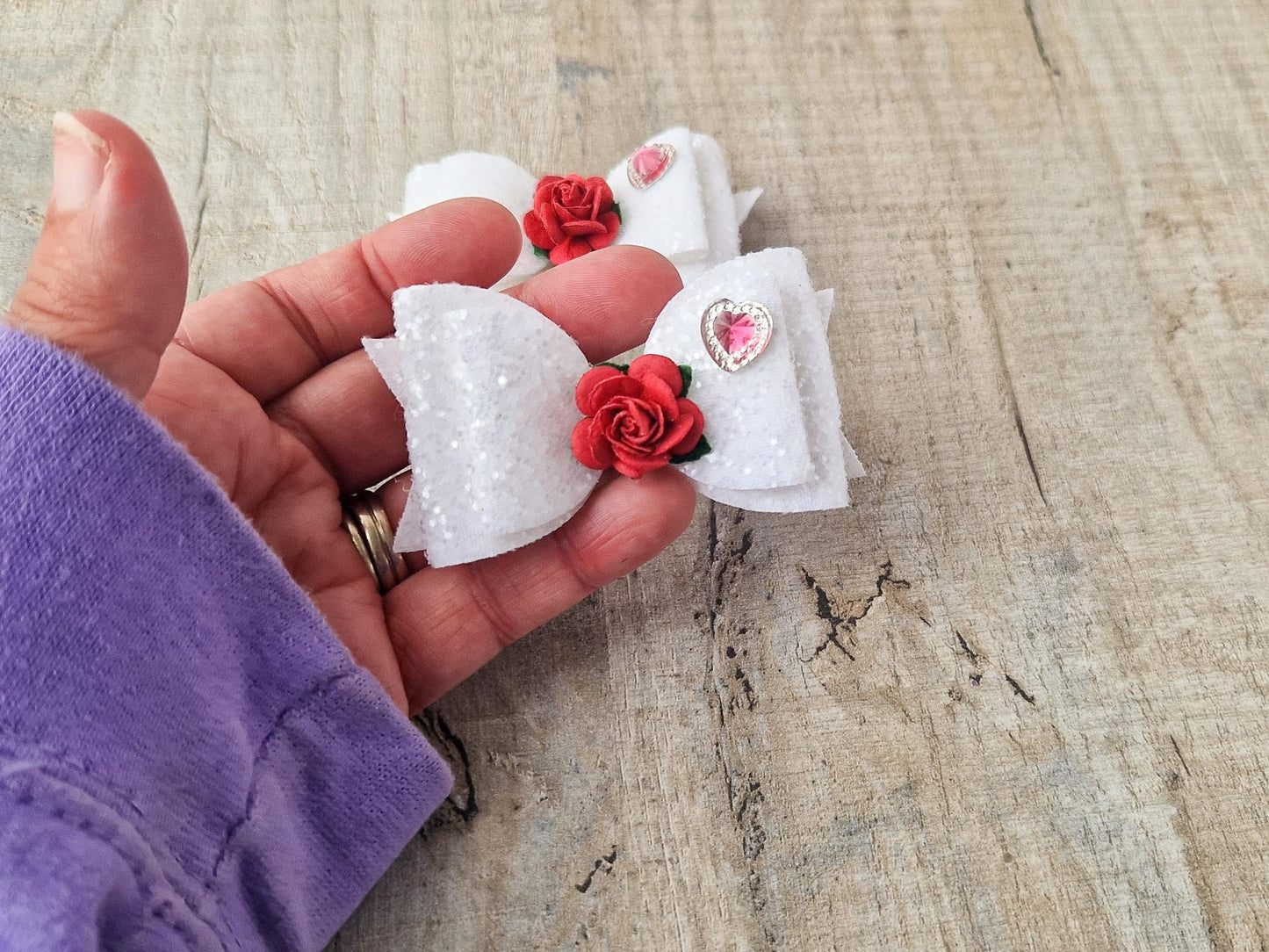 Beautiful Girls hair bow made with white Glitter and finished with a red rose and pink heart embellishment.